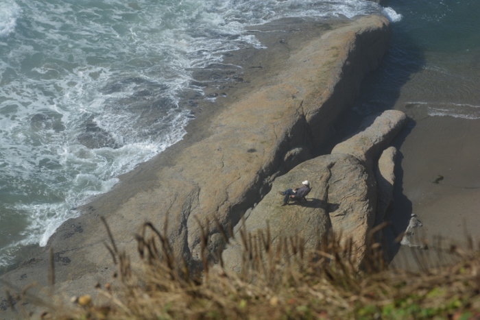 man sitting and reading on rock